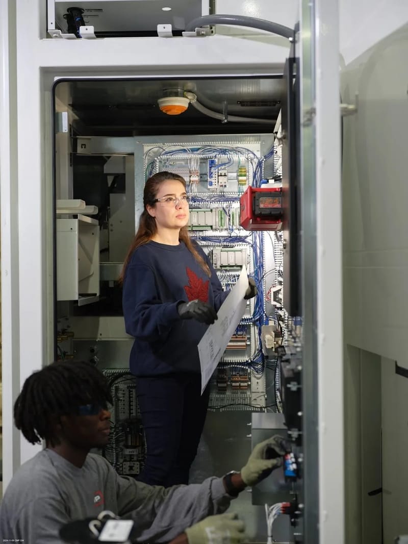 Technician inspecting wiring inside an electrical cabinet