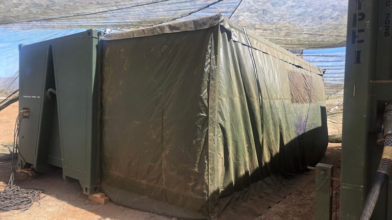 Field shelter with a canvas cover deployed on gravel