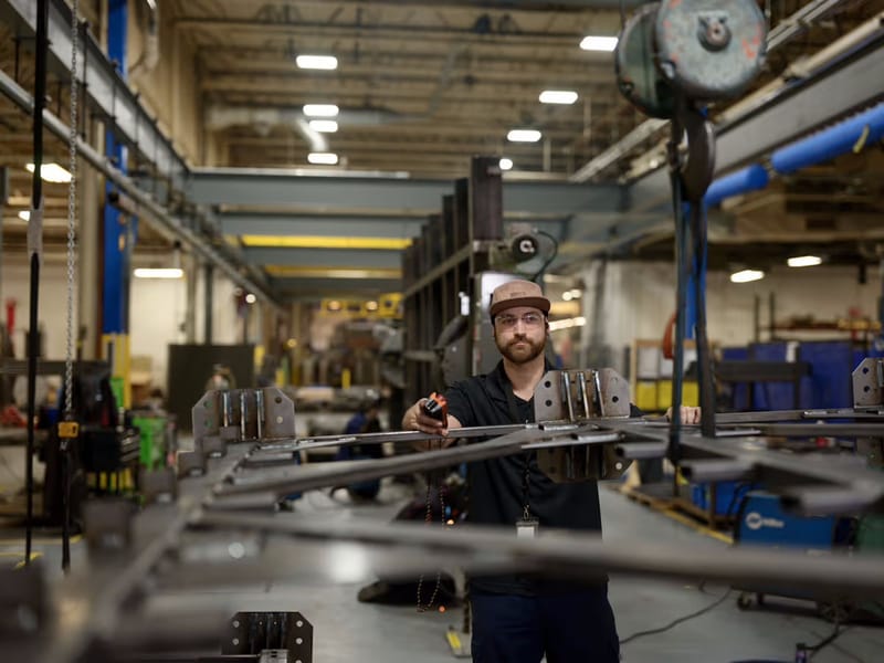 Technician guiding a metal frame through a press brake