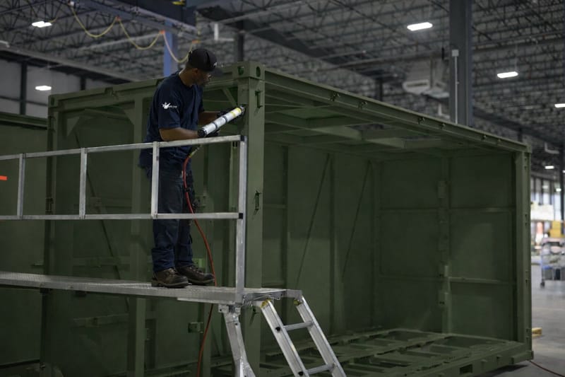 Worker on a ladder inside a container frame under construction
