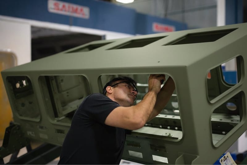 Technician fitting a panel inside a green enclosure frame