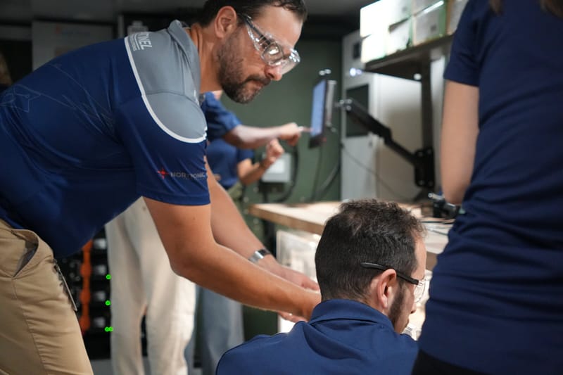 Two technicians checking an assembly against a tablet