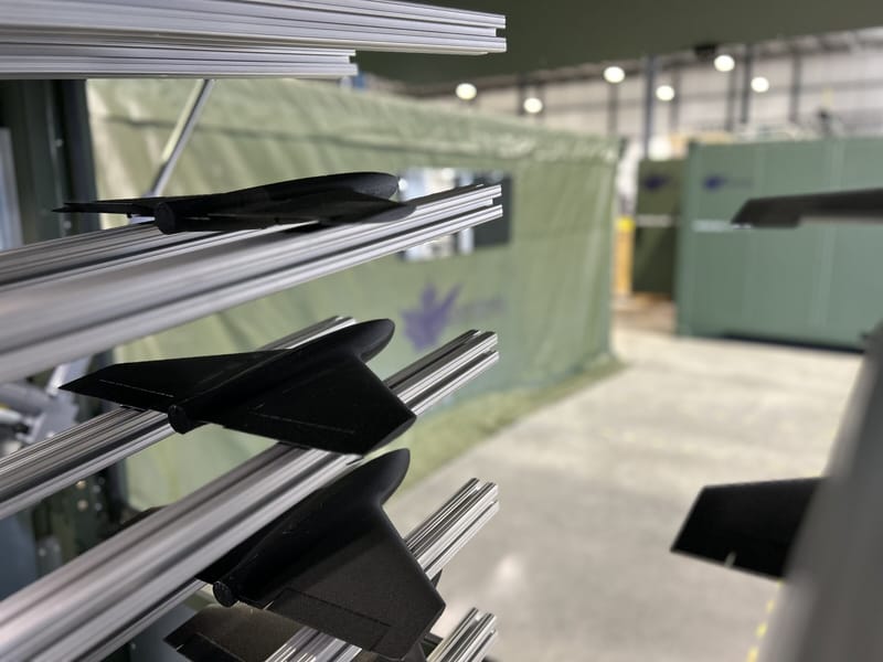 Rack of unmanned aircraft wings and components beside a field tent