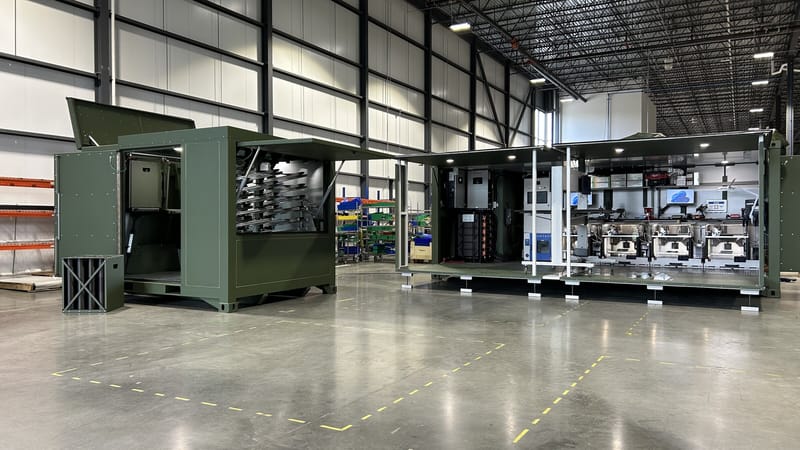 Two open StarForge units on the factory floor, with workstations and equipment inside