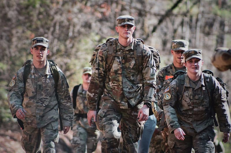 Soldiers walking in file through wooded terrain
